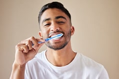 Man smiling while brushing his teeth