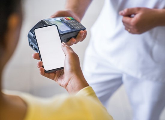 Woman in yellow sweater paying for services with her phone