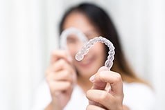 Smiling woman holding clear aligners