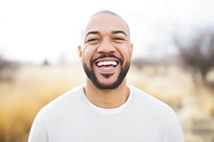 Man in white shirt smiling outside