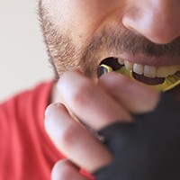 Man putting yellow mouthguard in mouth
